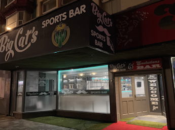 Facade of the Big Cat's sports bar at night.